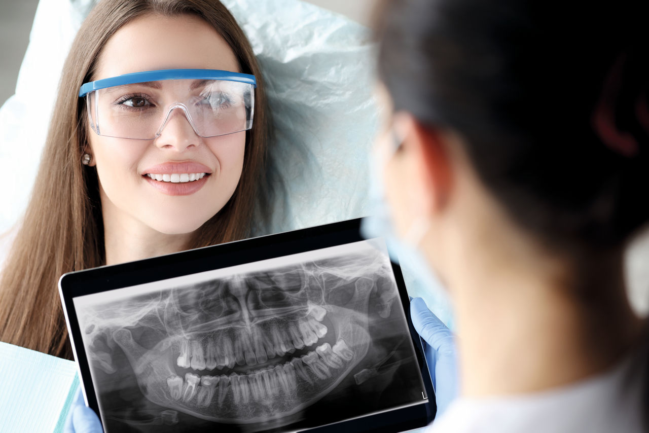 Dentist holding digital tablet with 3D picture of teeth in hands in front of female patient