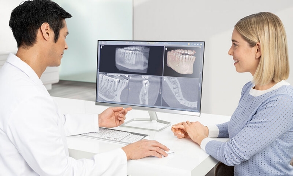 Dentist together with patient looking at monitor screens 