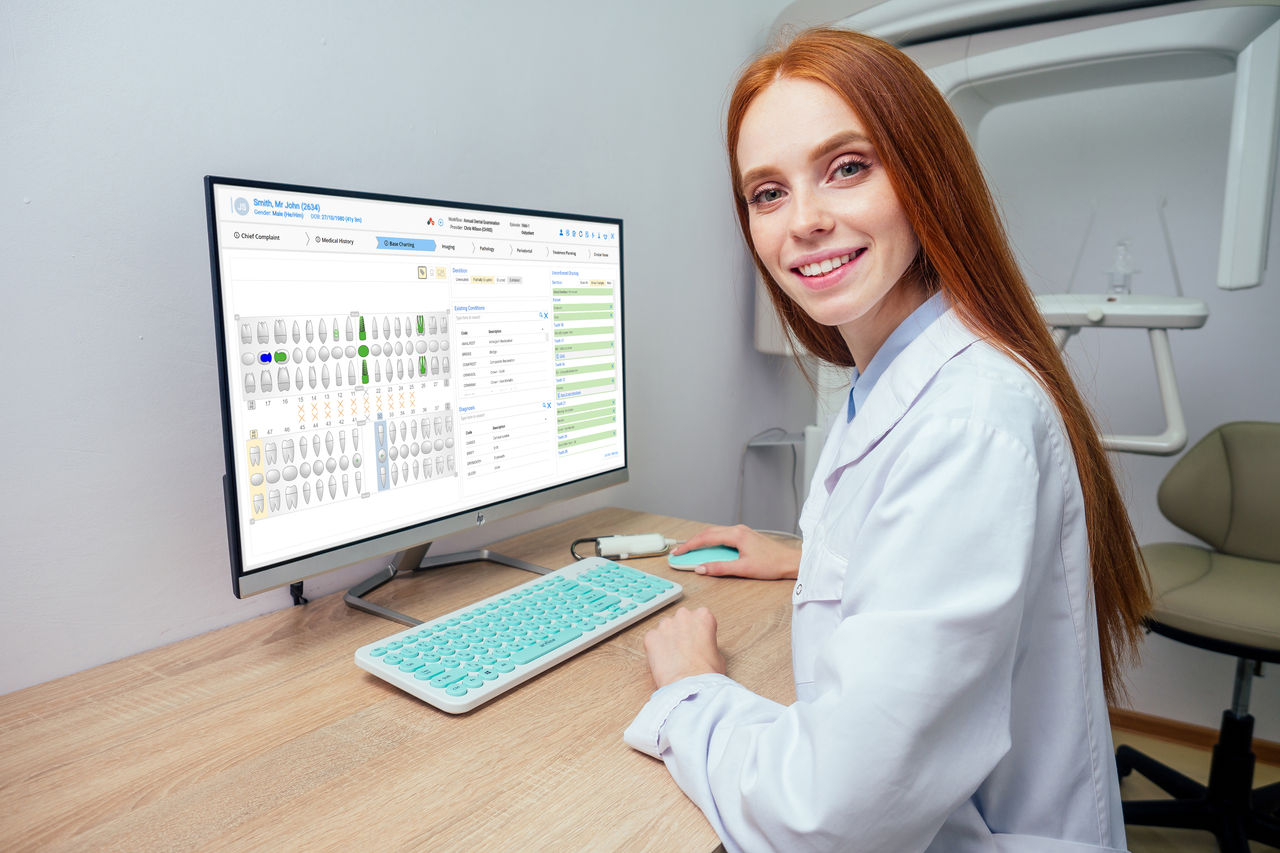 redhaired ginger female dentist showing mouth x-ray on computer.