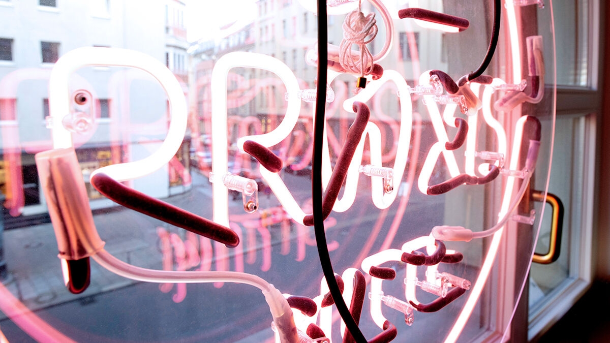 An eye-catcher in the window - lettering in neon pink of the Praxis Mitte, in Berlin.