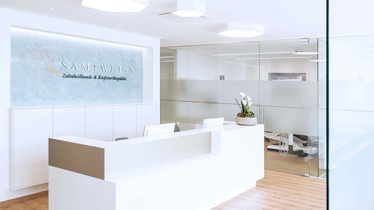 Reception desk in dentist's office in soft white. Glass walls in the background